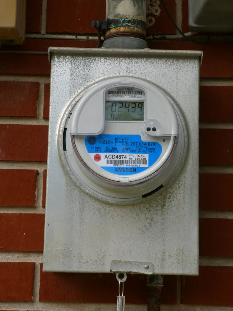 A digital electric meter on a brick wall.