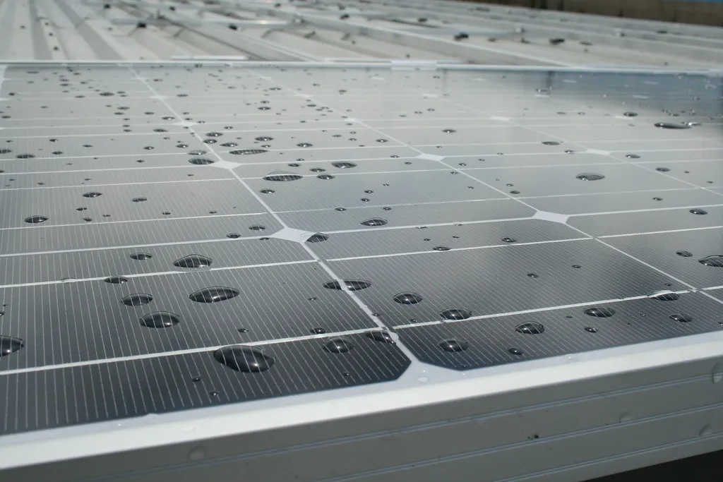 Raindrops beaded on the glass of a solar panel.