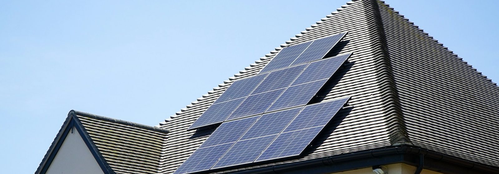 A tiled roof with three solar panels, each showing its grid of individual square cells.